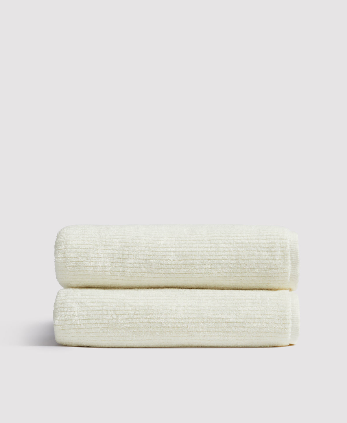 Two neatly folded cream-colored waffle weave blankets stacked on a white surface against a light gray background.