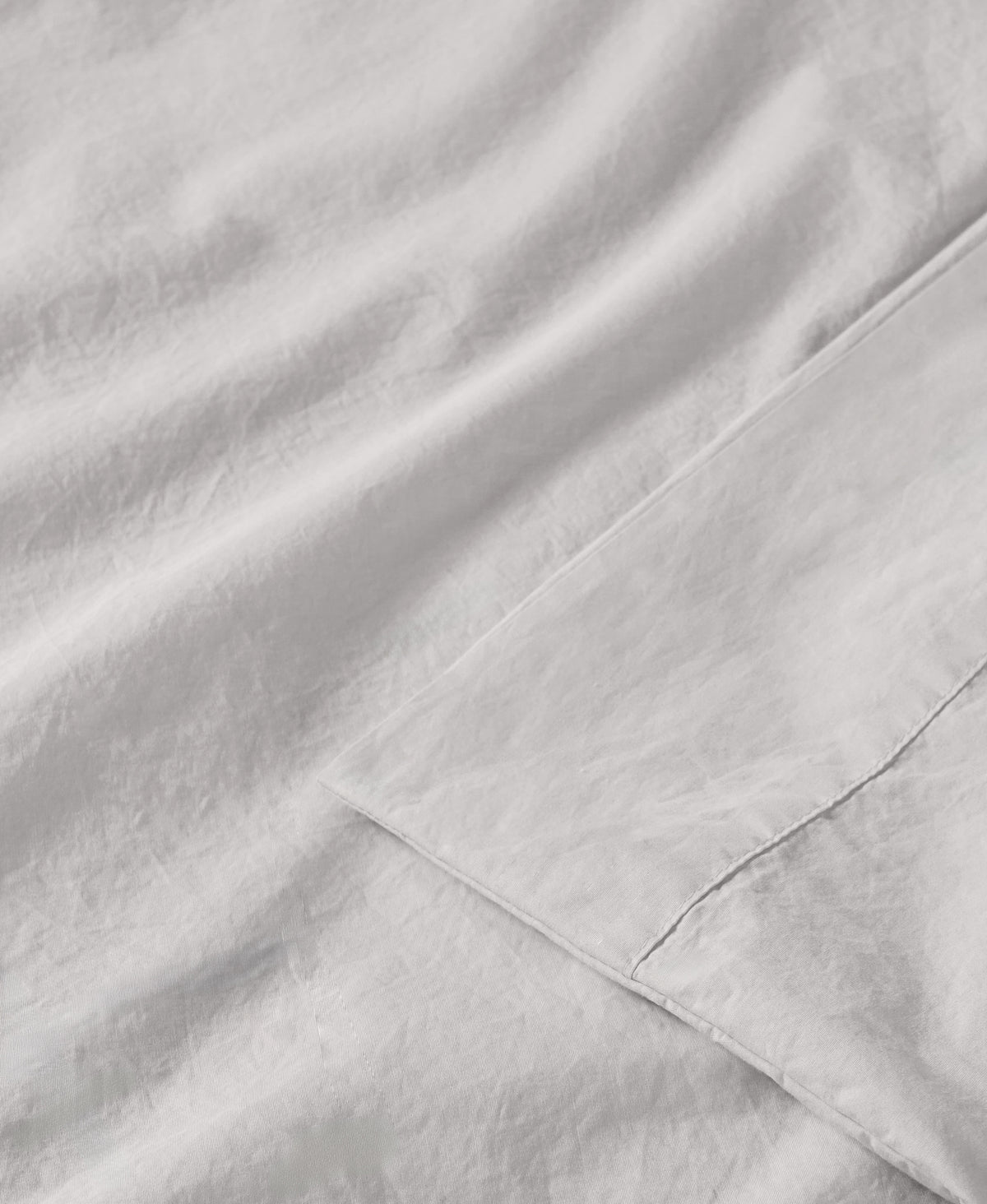White linen fabric with soft folds and visible stitched seam detail in natural lighting