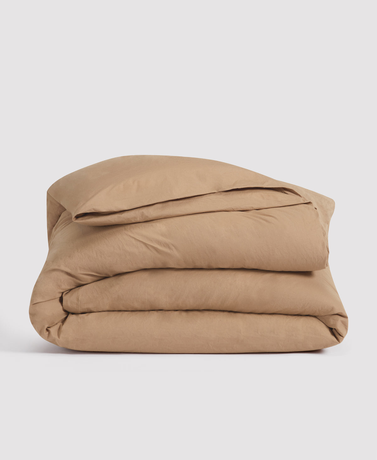 Folded beige duvet cover stacked neatly against white background, showing soft cotton bedding in neutral tan color