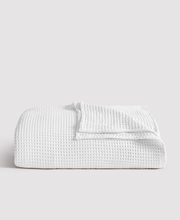 White waffle-textured blanket folded neatly against light gray background