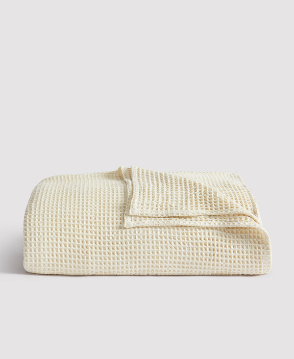 Cream-colored waffle weave blanket folded neatly against white background