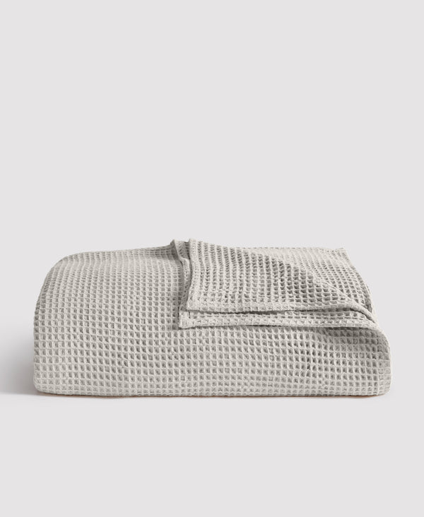 Gray waffle weave blanket folded neatly against white background