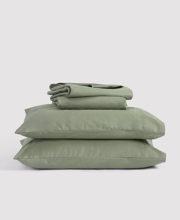 Blue and white zigzag patterned bedding set with folded duvet cover and stacked pillows on light gray background