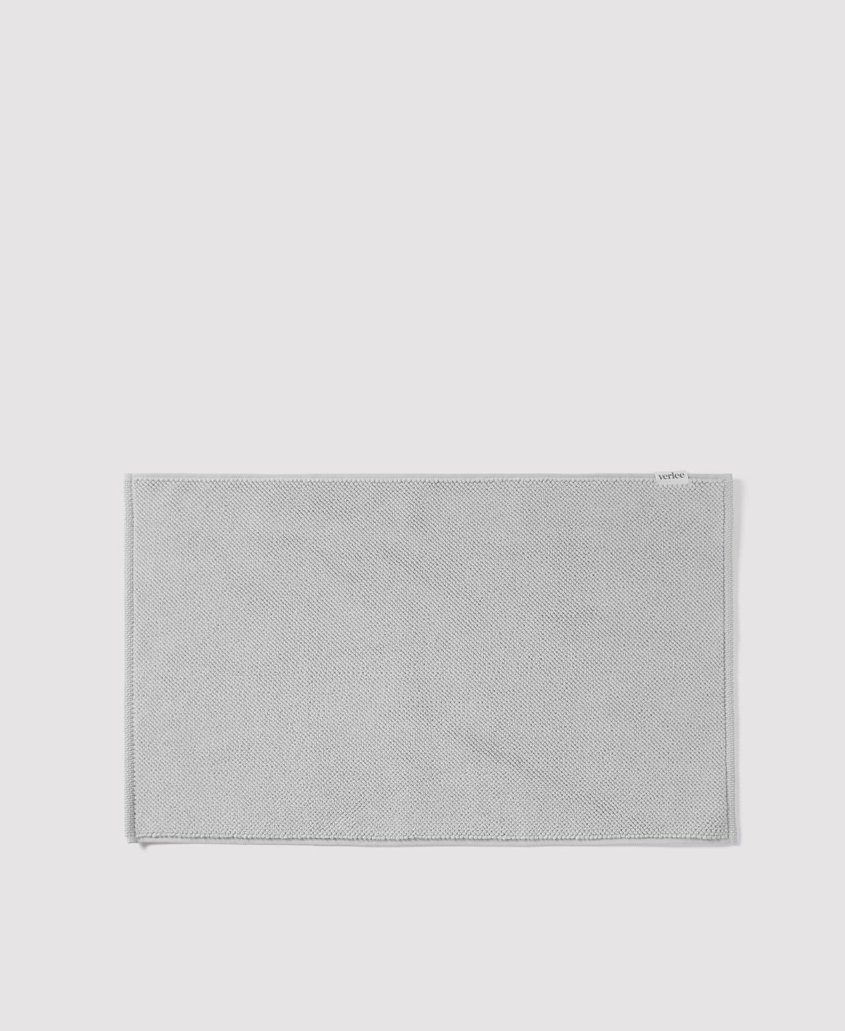 Gray woven textile bath mat or rug with herringbone pattern and bordered edges on white background