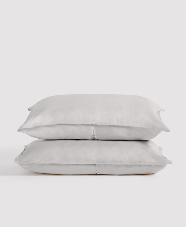 Stack of two white linen pillowcases against a light gray background