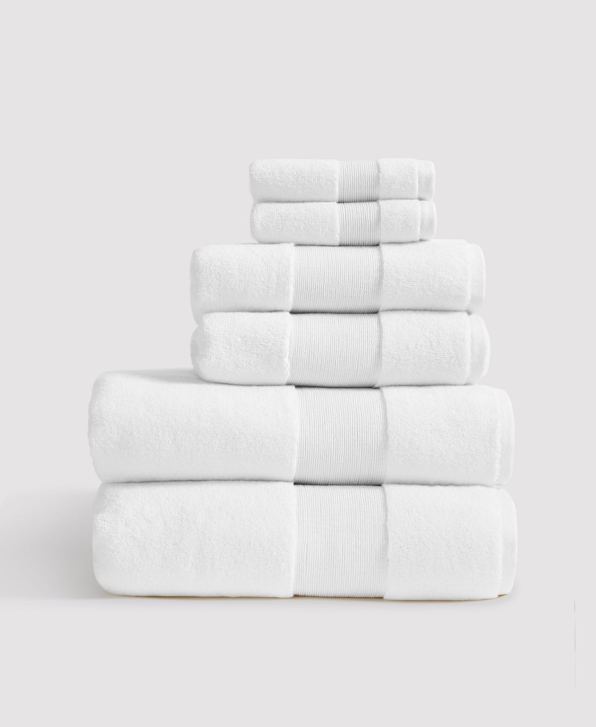 Stack of six neatly folded white towels with ribbed borders arranged by size from largest at bottom to smallest at top
