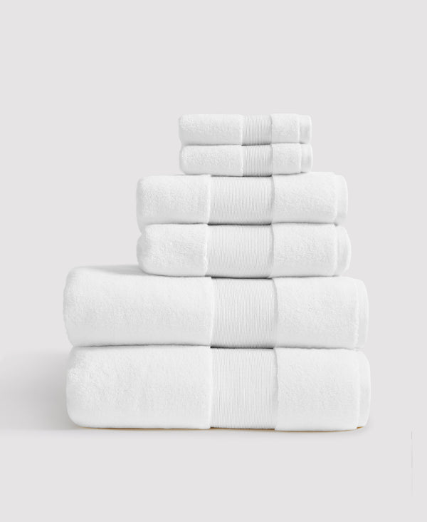 Stack of six neatly folded white towels with ribbed borders arranged by size from largest at bottom to smallest at top
