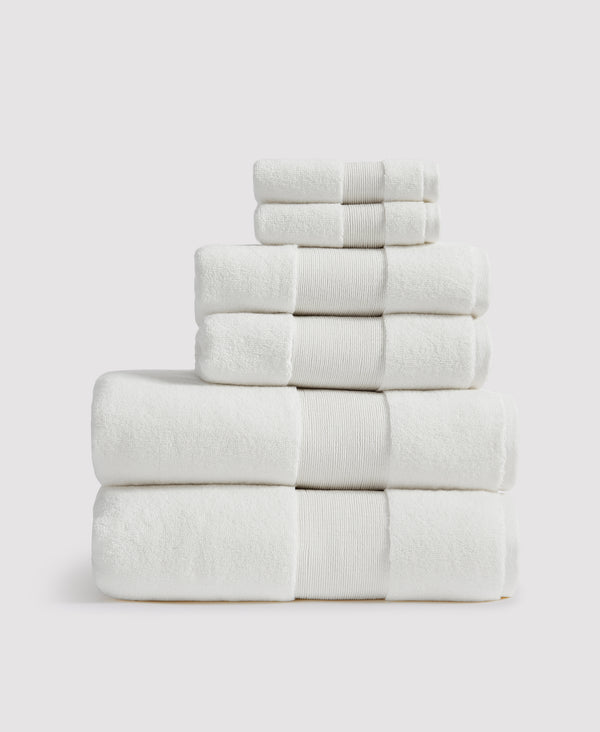 Stack of six neatly folded white towels with ribbed borders arranged by size from largest at bottom to smallest at top
