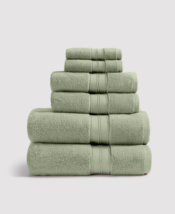 Stack of six sage green terry cloth towels with decorative striped borders arranged by size on white background