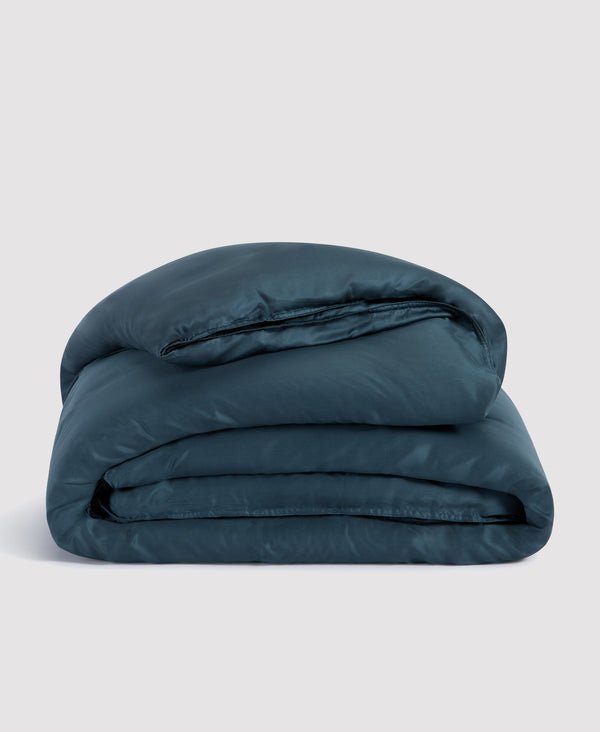 Folded teal blue comforter or duvet set stacked neatly against white background