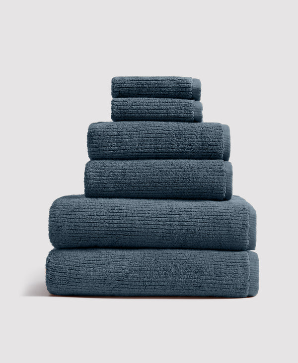 Stack of six neatly folded teal-gray towels arranged by size from largest at bottom to smallest at top