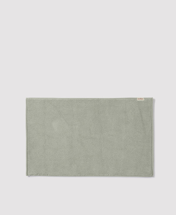 Sage green woven placemat with "Artex" brand label on light gray background