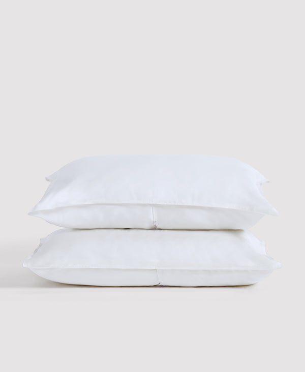 Two white pillows stacked against a light gray background in minimalist bedroom setting