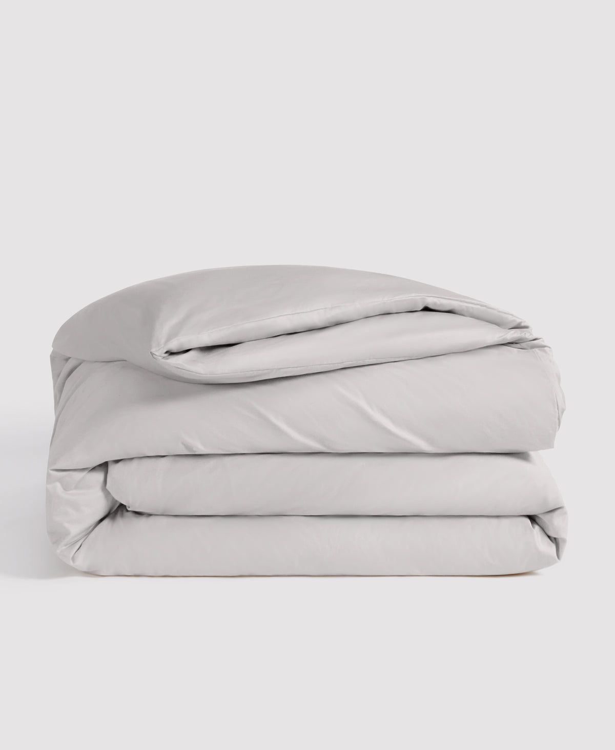 Light gray folded duvet cover and pillowcase bedding set stacked against white background