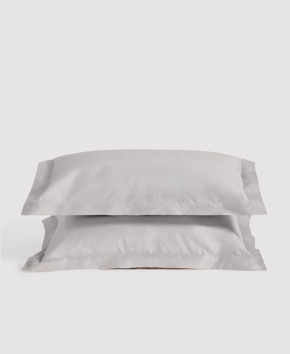 Two soft gray linen pillowcases stacked against a light gray background