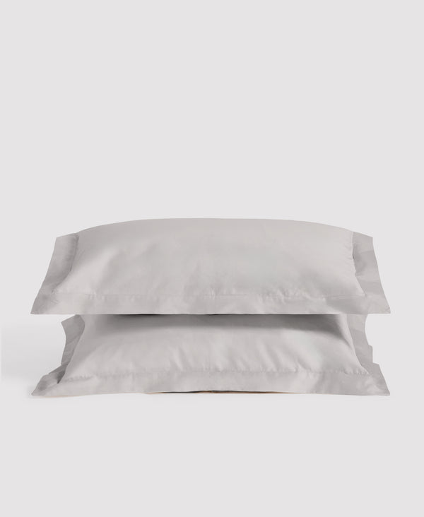 Two soft gray linen pillowcases stacked against a light gray background