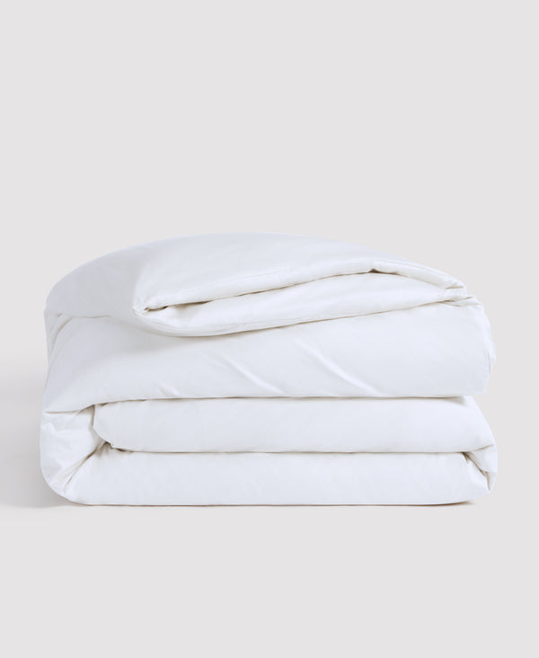 White folded comforter or duvet neatly stacked against a light gray background