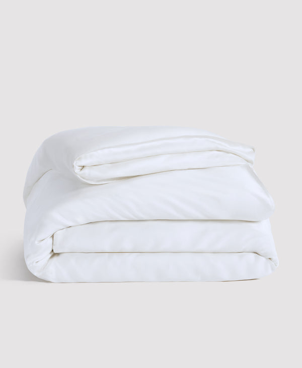 White folded comforter or duvet neatly stacked against a light gray background