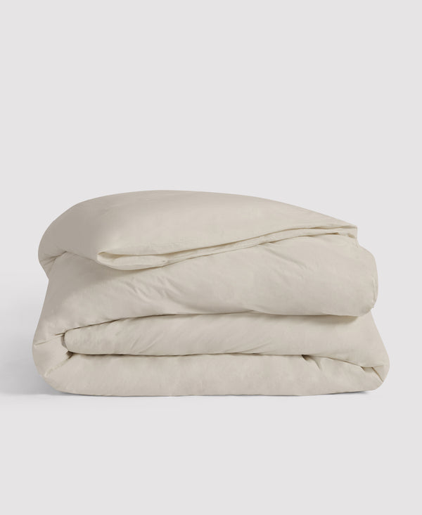 Folded cream-colored duvet cover neatly stacked against white background