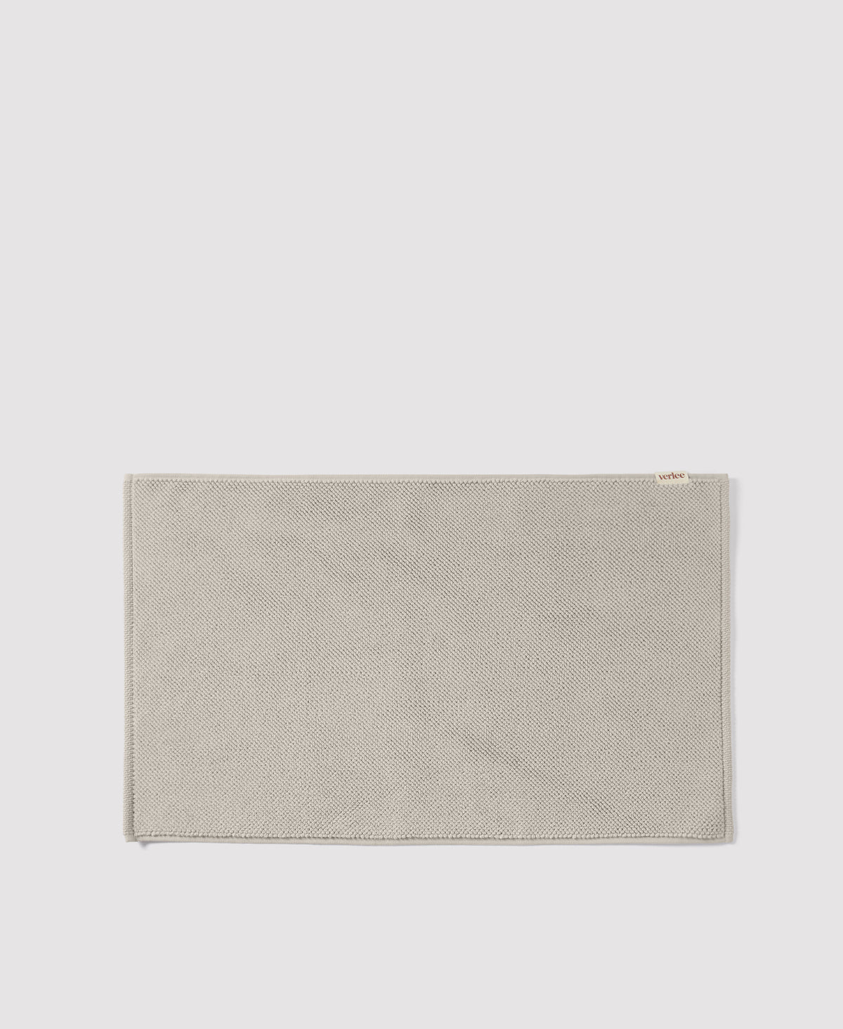 Olive green woven textile placemat with herringbone pattern and small white label on light gray background