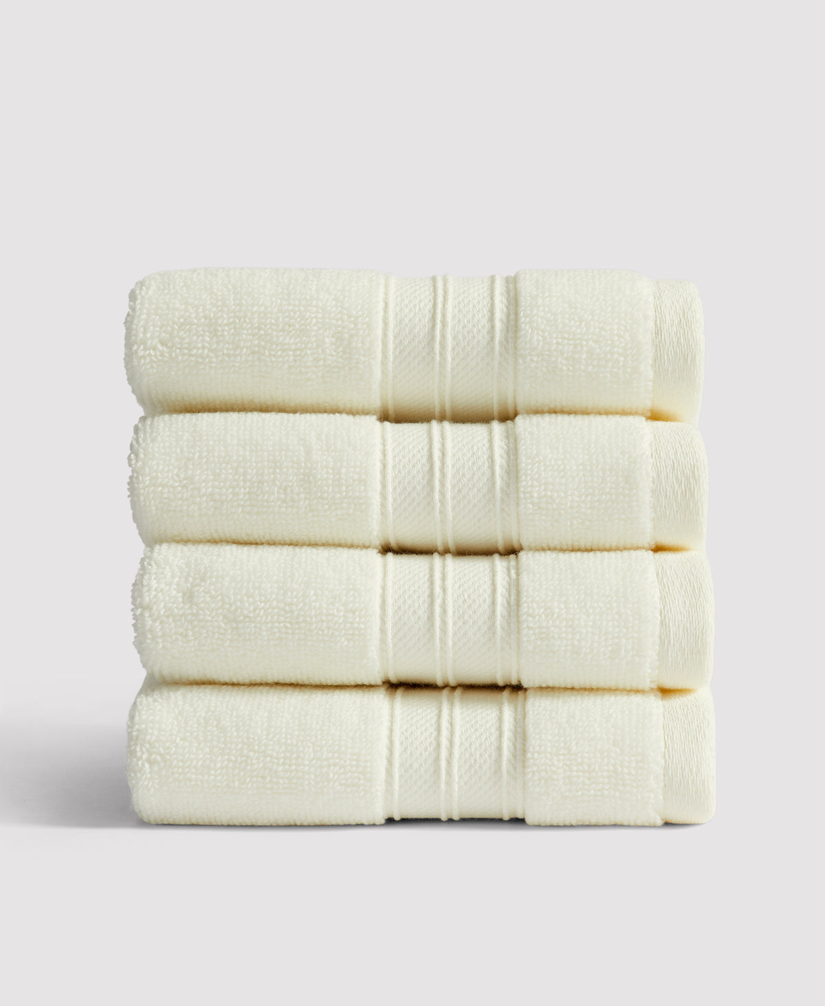 Stack of four neatly folded cream-colored towels with decorative striped borders against white background