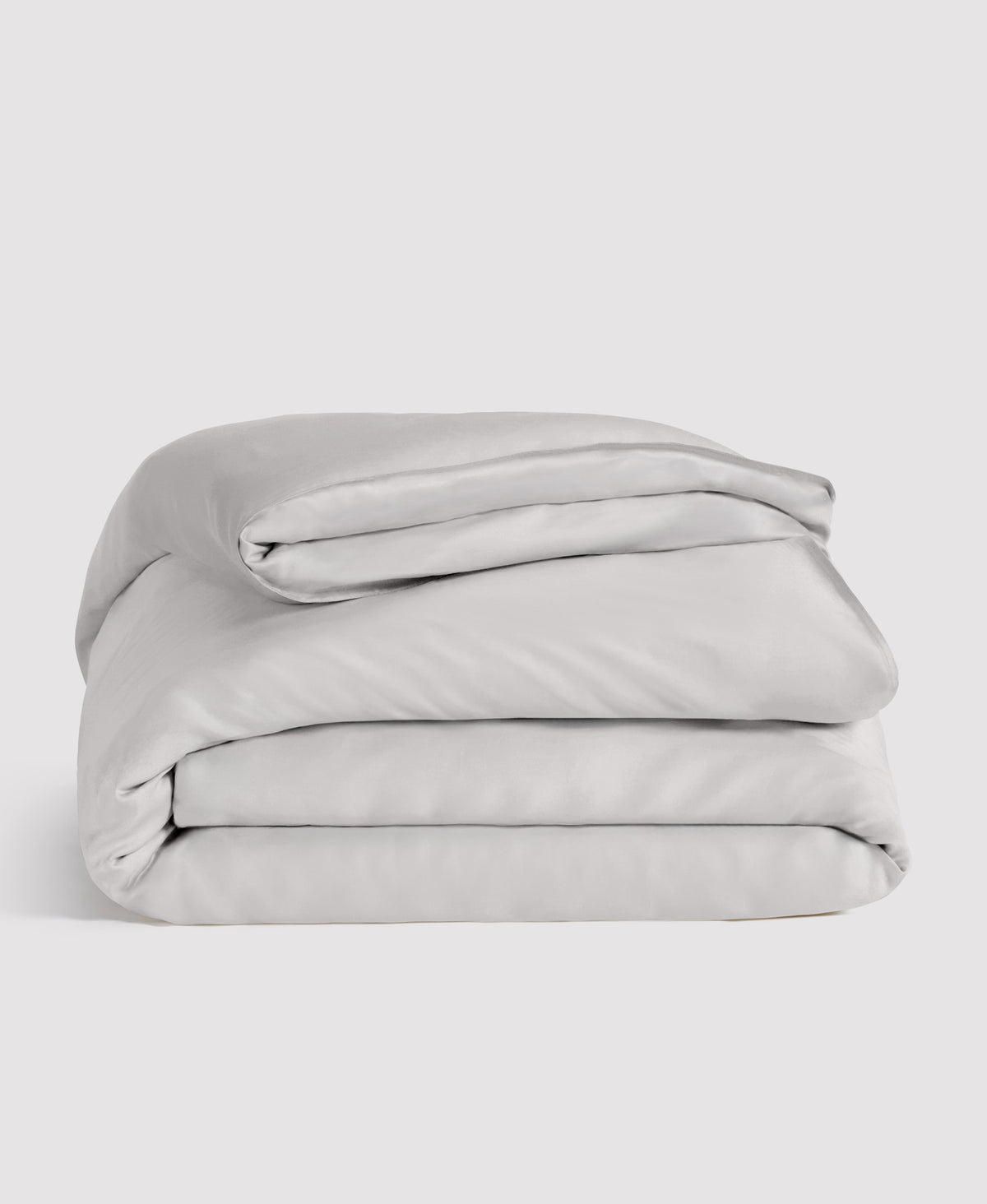 Light gray folded duvet cover with matching pillowcases stacked neatly against white background