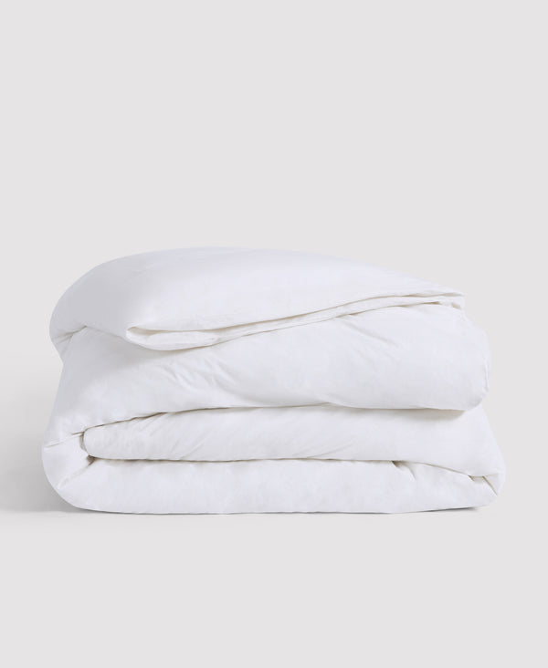 White folded comforter or duvet neatly stacked against a light gray background