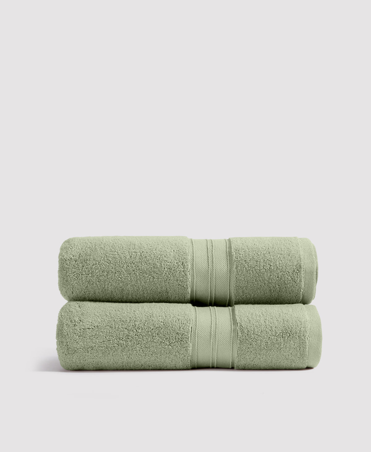 Two sage green bath towels neatly stacked with decorative striped borders on white background